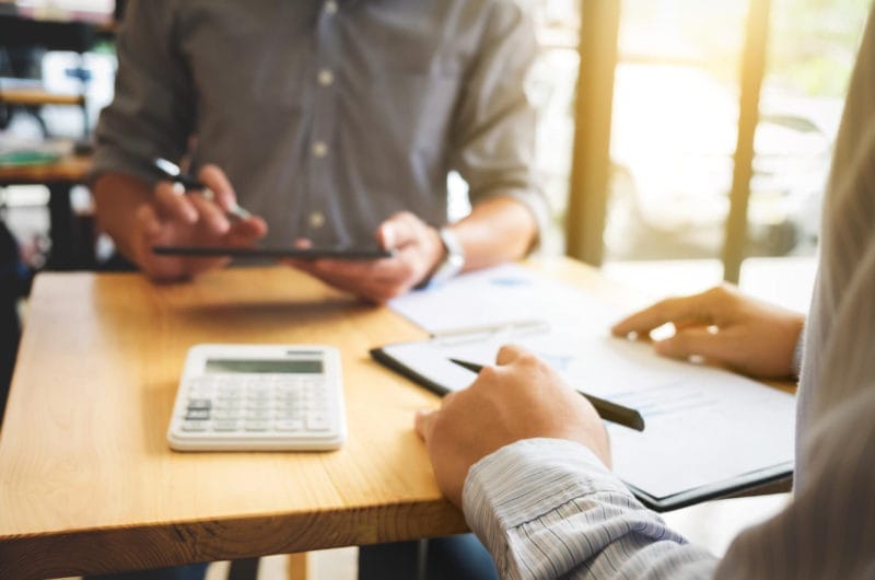 Agent financier analysant les besoins bancaires de clients lors d’une réunion, conseils pour choisir la meilleure banque et services bancaires adaptés.